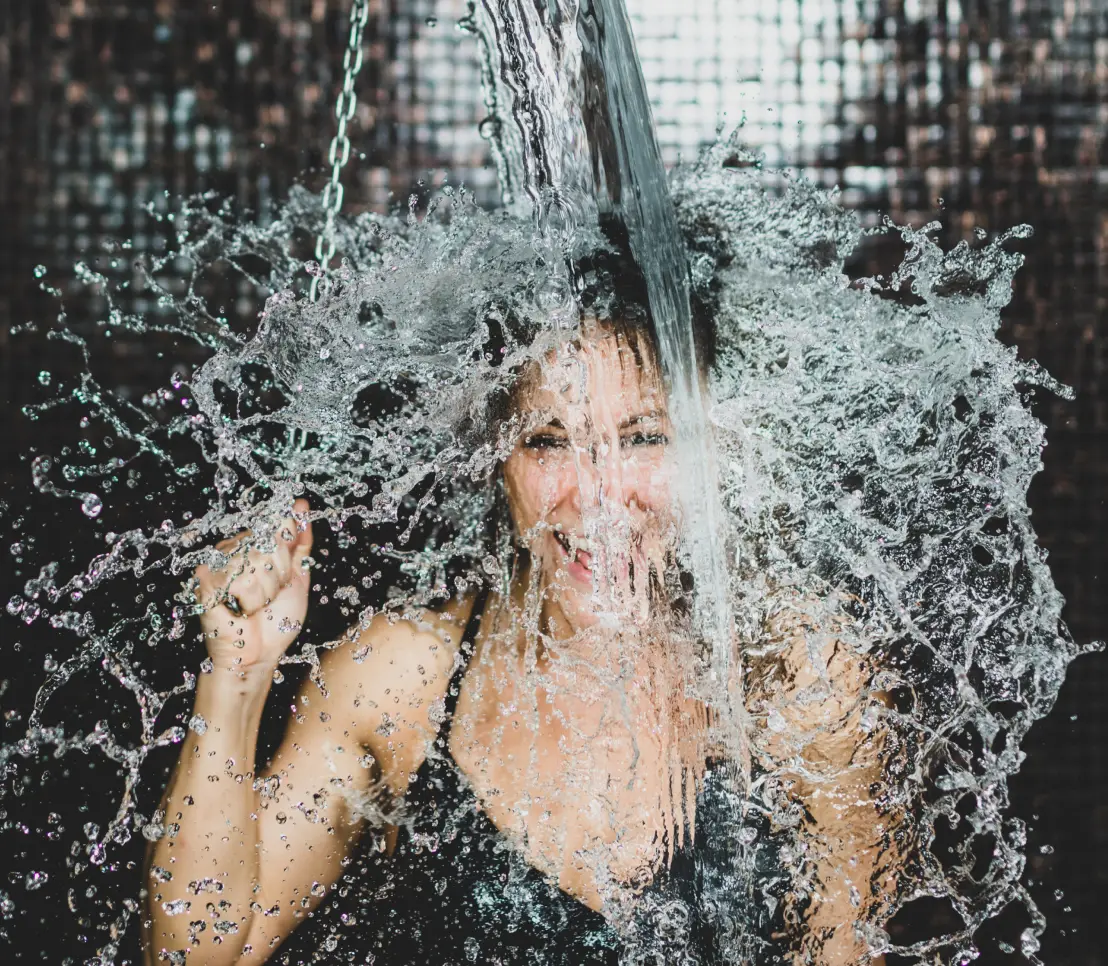 Women pulling the chain of an ice cold deluge bucket shower to kick start metabolism