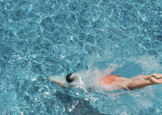 Athletic man diving in to luxury designed outdoor swimming pool