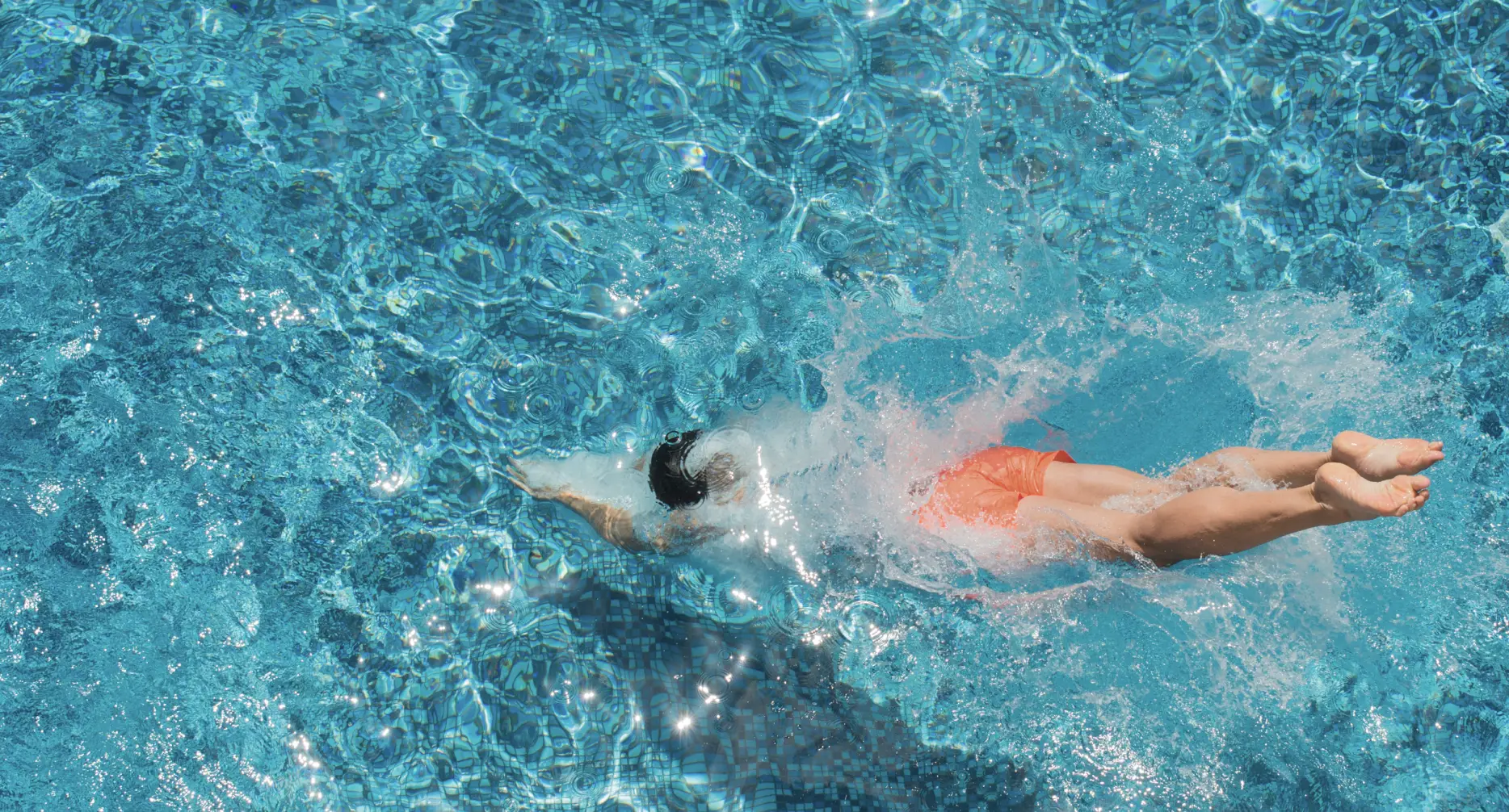 Athletic man diving in to luxury designed outdoor swimming pool