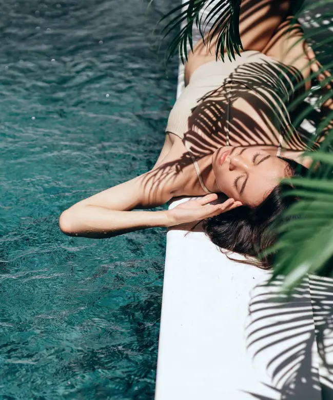 Women laying down relaxing on the side of luxury outdoor pool